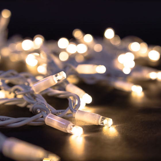 Warm white fairy lights with white cable illuminated on dark floor